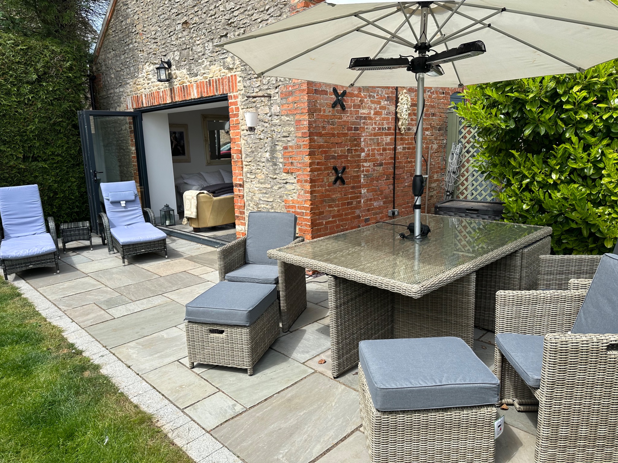 Private patio with outdoor dining table, umbrella and loungers beside the Coach House