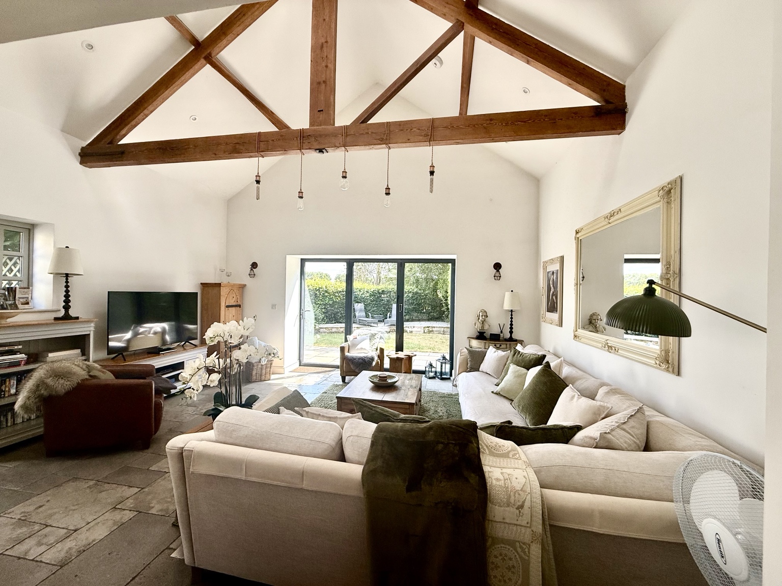The Coach House living room with exposed timber beams, comfortable sofas and doors to the garden